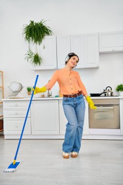 A stylish woman in casual attire gracefully cleaning the floor with a mop, bringing sparkle and cleanliness to her home. clipart