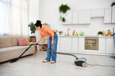 A stylish woman in casual attire efficiently vacuums a living room, leaving it spotless and fresh. clipart