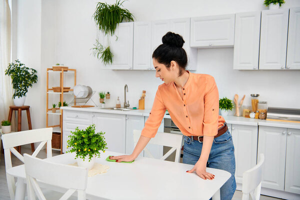 A stylish woman in casual attire meticulously wipes down a table in a home kitchen, creating a gleaming and inviting space.