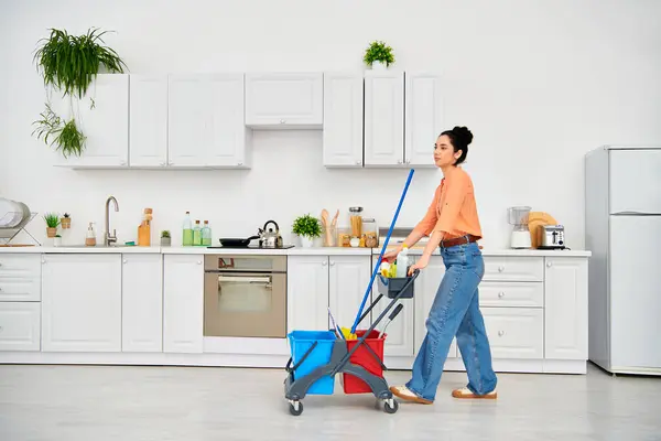 一个时髦的女人不费吹灰之力地在光滑的厨房里推着一辆购物车 展示了她在家务活中毫不费力的风格和优雅 — 图库照片