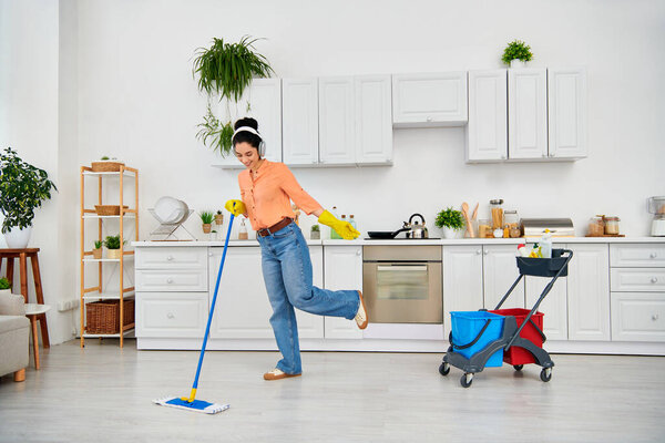 A stylish woman in casual attire gracefully mops the floor at home, adding elegance to her cleaning routine.