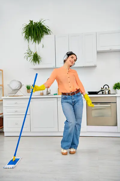 一个穿着休闲装的时髦女人用拖把优雅地清洁地板 给家里带来了火花和洁净 — 图库照片