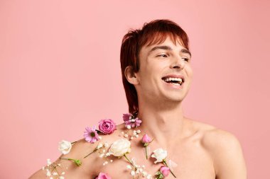 A shirtless young man proudly displays a variety of colorful flowers arranged artistically on his chest in a studio setting. clipart