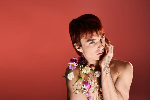 A young man adorned with flowers in a studio against background.