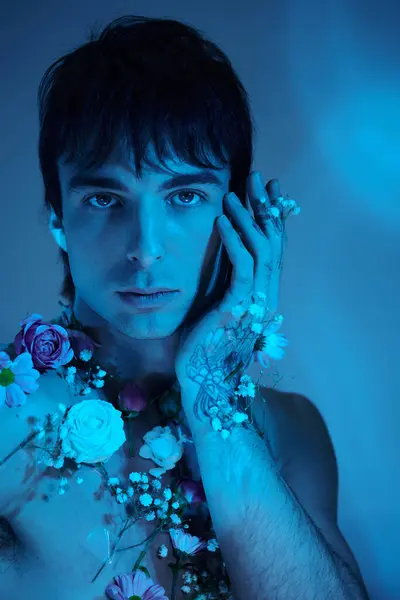 stock image A young man confidently stands shirtless, adorned with vibrant flowers