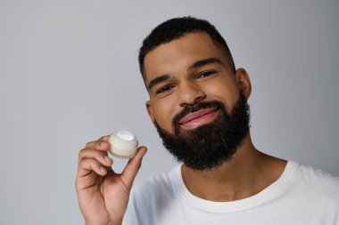 Sakallı yakışıklı adam elinde krema kavanozu tutuyor..