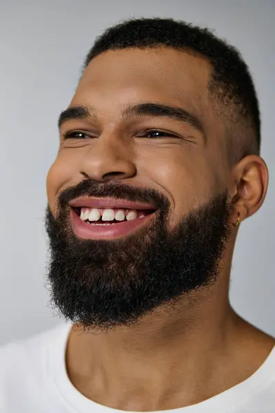 stock image A young man with a beard smiling warmly at the camera.