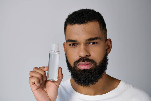 Handsome man with a beard holding a bottle of locion.