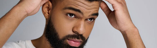 A young man with a beard taking care of his hair.