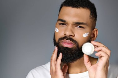 Afro-amerikan çekici genç adam yüzüne krem sürüyor..