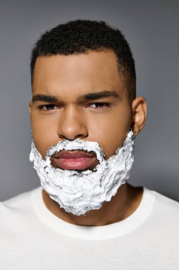 Afrikalı Amerikalı genç bir adam cilt bakımının bir parçası olarak yüzünü yakından tıraş eder..