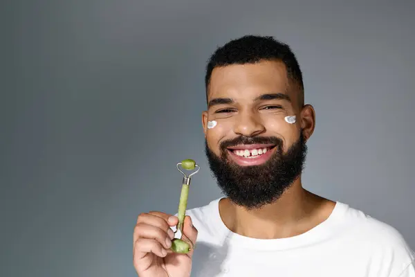 African American Cheerful Man Cream His Face Using Face Roller — Zdjęcie stockowe