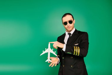 Stylish man in black suit and sunglasses holding a model airplane. clipart