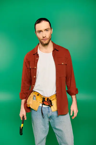 Man Red Shirt Holds Yellow Tool Belt Green Backdrop — Stock Photo, Image