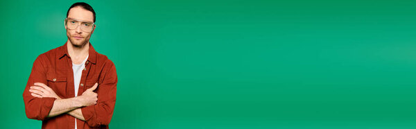 Handsome male worker in uniform with crossed arms against a green backdrop.