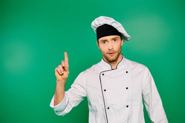 Handsome chef in white uniform confidently pointing towards the camera. clipart