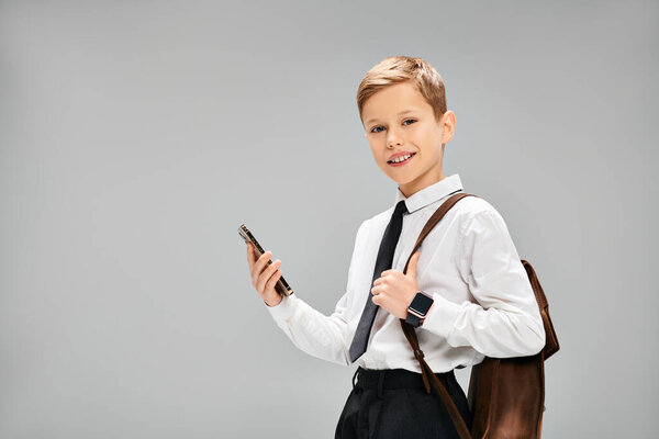Маленький мальчик в белой рубашке, галстук, держит мобильный телефон.