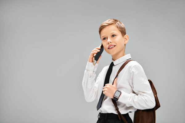 Молодой мальчик в элегантной одежде держит телефон у уха.