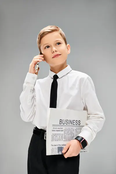 stock image A preadolescent boy in business attire holding a newspaper.
