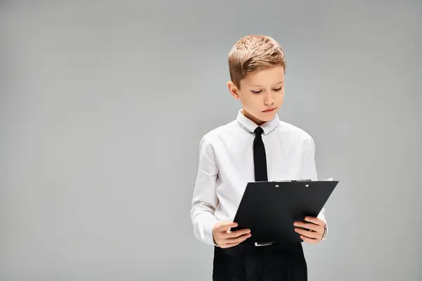 stock image A preadolescent boy in white shirt and tie holds a black folder.