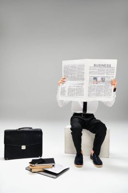 Man in elegant attire reading newspaper while sitting on bench. clipart