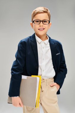 Young boy in glasses with book in hand, exuding intelligence. clipart