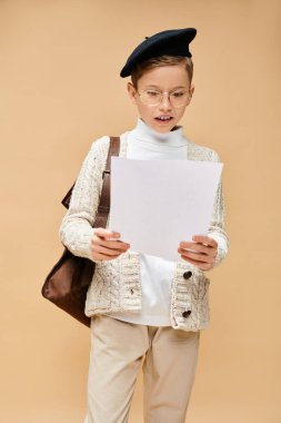 Cute preadolescent boy dressed as a film director, holding a piece of paper. clipart