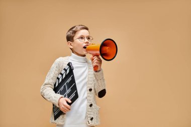 A young boy dressed as a film director holding a red and orange megaphone. clipart