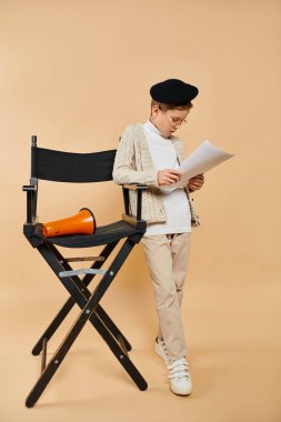 Film yönetmeni gibi giyinmiş, katlanan sandalyede gazete okuyan genç bir çocuk..