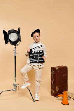 A boy directs a film scene with a clapper in front of a camera. clipart