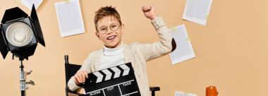 A woboy holds a clapboard in front of a camera. clipart