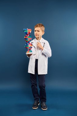 Doktor gibi giyinmiş ergen bir çocuk, bir yapı modeli tutuyor..