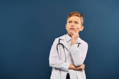 Young boy in white coat and stethoscope on blue backdrop. clipart