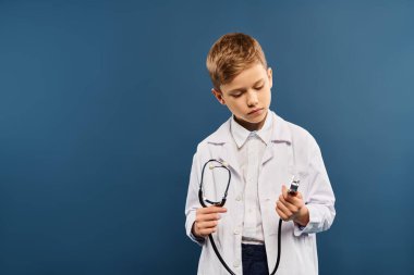 A cute preadolescent boy in a lab coat, holding a stethoscope. clipart