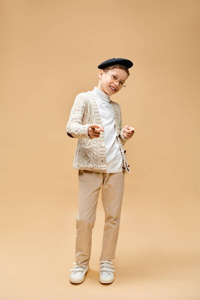 A cute preadolescent boy dressed as a film director on a beige backdrop.