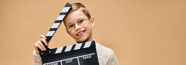 Preadolescent boy mimics a film director with clapper board.