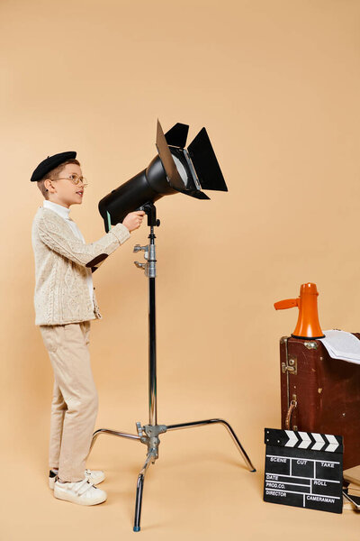 Preadolescent boy stands confidently next to camera and tripod.