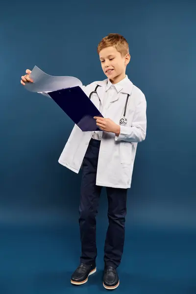 Young Boy Lab Coat Holding Clipboard Blue Backdrop — Stock Photo, Image