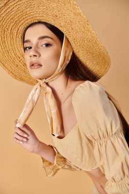 Uzun esmer saçlı genç bir kadın yaz kıyafetiyle poz verir, hasır şapka takar ve şık bir eşarp takar..