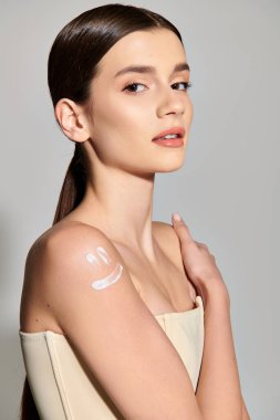 A young woman with brunette hair stands in a studio setting, her arm adorned with an abundant amount of cream. clipart