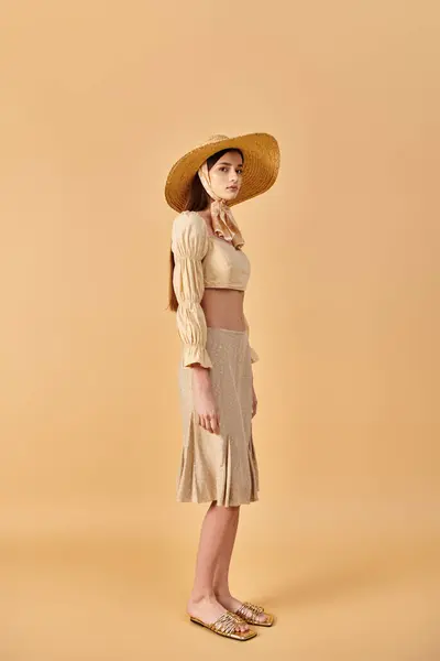 stock image A young woman with long brunette hair poses in a straw hat and dress, embodying a carefree summer mood.