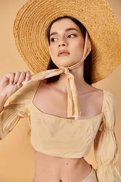 長いブルネットの髪を持つ若い女性がスタジオの設定でポーズを打ち わら帽子と夏のバイブを除く活気に満ちた黄色のトップを身に着けています — ストック写真