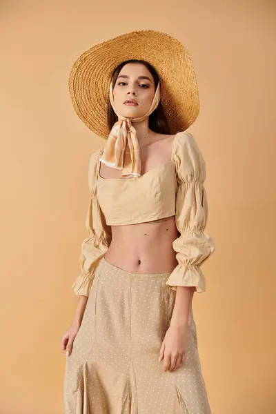 stock image A young woman with long brunette hair strikes a pose in a straw hat, exuding a summery and carefree vibe in a studio setting.