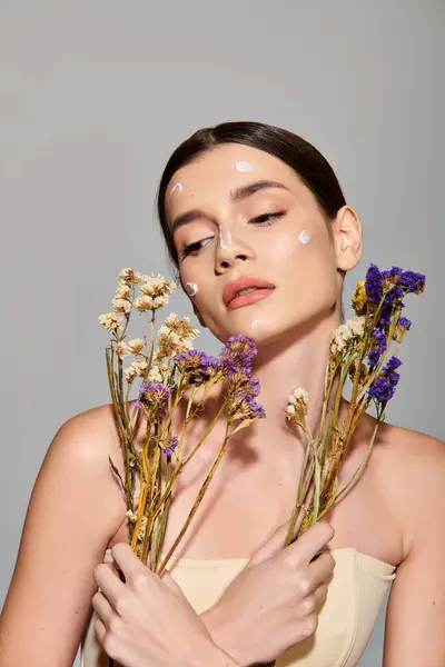 Stock image A young woman with brunette hair holds a bouquet of vibrant flowers in her hands, exuding natural beauty and grace.