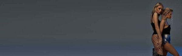 Две очаровательные молодые женщины позируют в коротких юбках и на высоких каблуках, выражая уверенность и стиль.