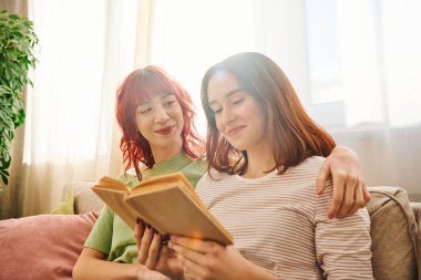Mutlu lezbiyen çift birlikte kitap okumaktan zevk alıyor, sevgi ve rahatlıkla sarılıyorlar.