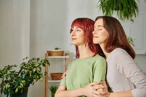 stock image portrait of young lesbian couple embracing while looking away, their faces full of bliss and joy