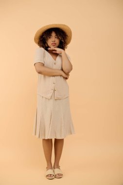 Stüdyo ortamında şapka ve yaz elbisesi giyen kıvırcık saçlı güzel bir Afrikalı Amerikalı kadın..