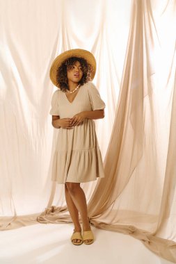 A stylish young African American woman with curly hair, wearing a hat, stands confidently against a white backdrop in a studio. clipart