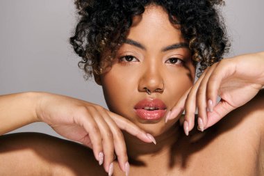 Kıvırcık saçlı, burun halkası takan, kendine güvenen güzel bir Afro-Amerikan kadın..
